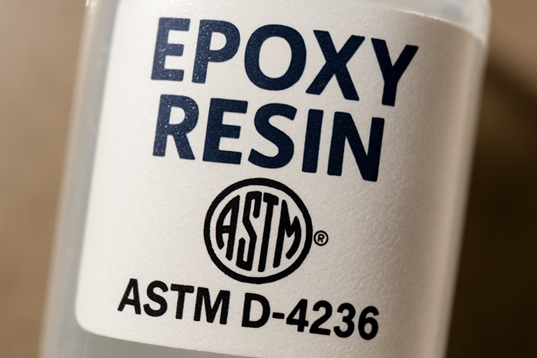 Close-up of an ASTM D-4236 certification logo on an epoxy resin bottle label, indicating non-toxic compliance.